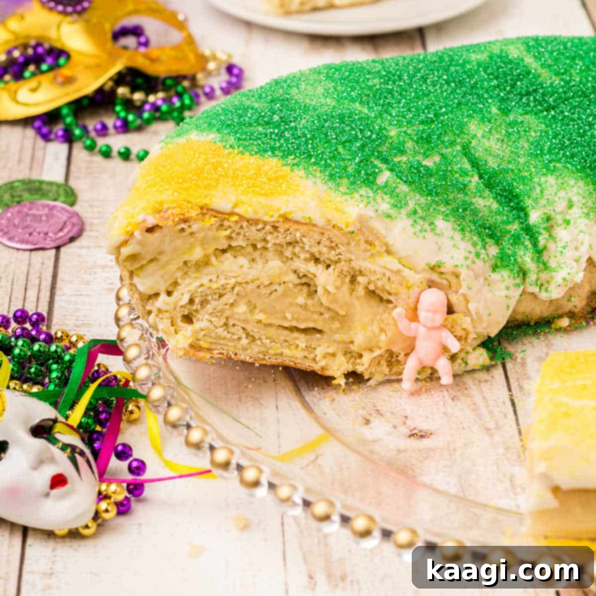 A festive King Cake with a slice cut out, revealing the traditional baby figurine.