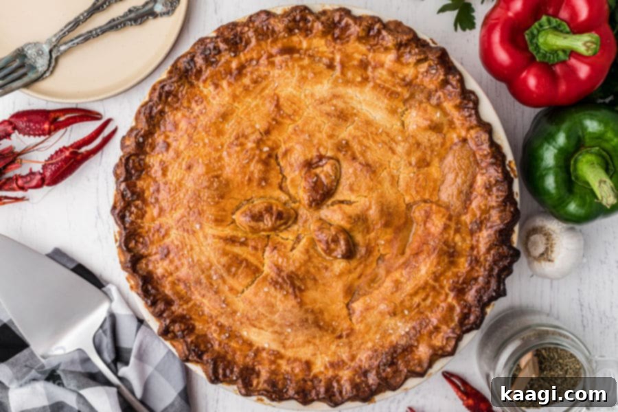 A golden brown Crawfish Pie surrounded by bell peppers and cooked crawfish tails.