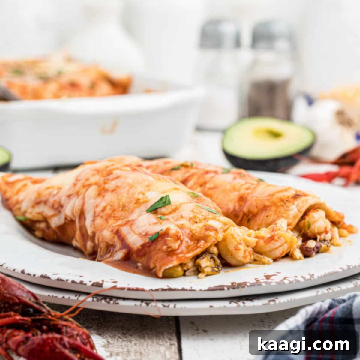 A close-up of a plate of Crawfish Enchiladas, garnished with fresh avocado slices in the background.