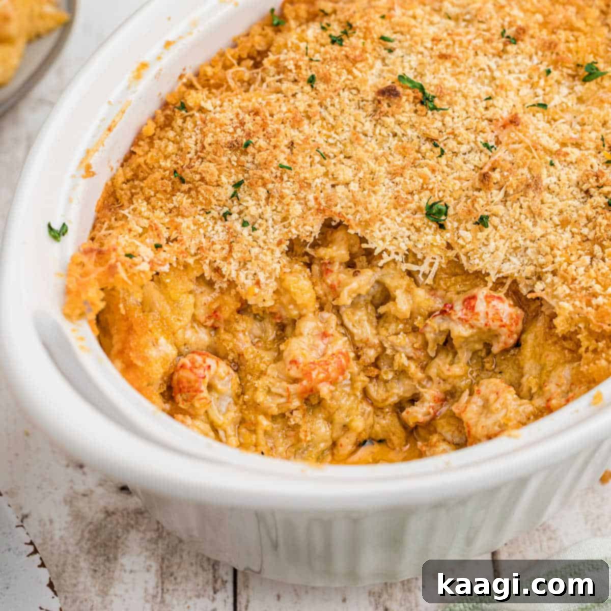A baking dish of creamy, cheesy Crawfish Au Gratin, with a large portion already served.