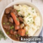 Overhead shot of a bowl full of Irish Stew with Mashed Potatoes, cropped square.