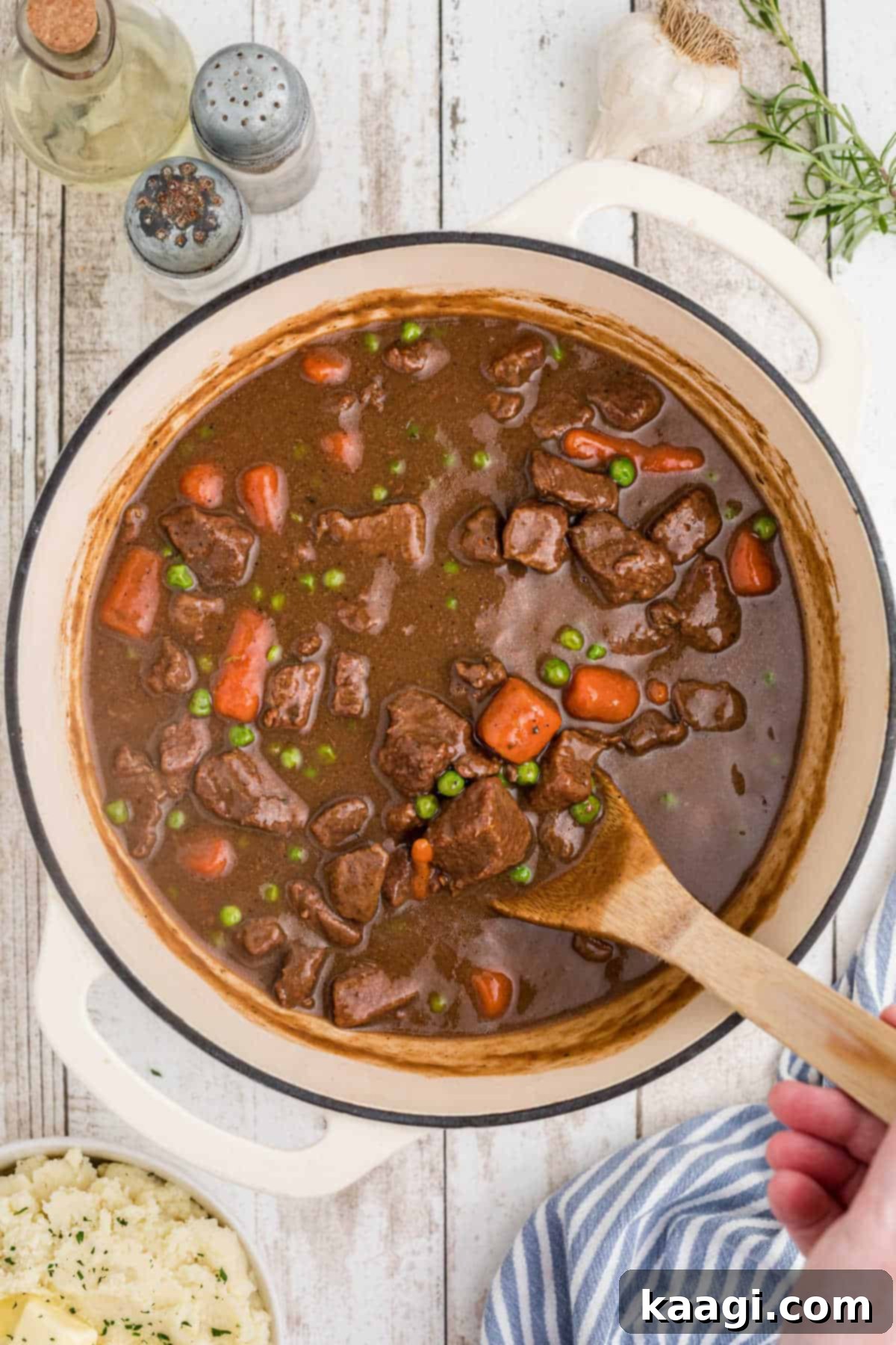 Overhead shot of a pot full of Irish Stew with a spoon stirring it.