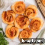 A close up overhead shot of a plate full of golden puff pastry pizza pinwheels, perfectly cropped square.