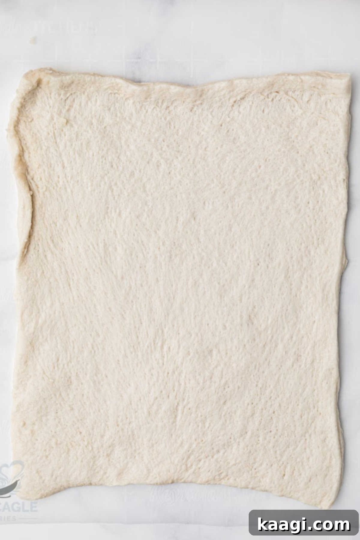 An unrolled sheet of puff pastry laid out on parchment paper.